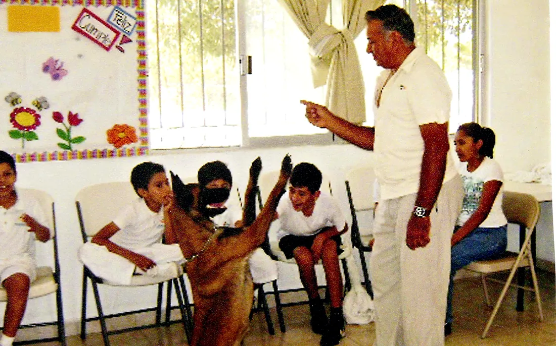 Rodolfo guía a un pastor belga malinois durante una sesión de terapia con niños.